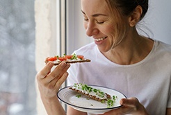Woman smiling while eating healthy snack at home
