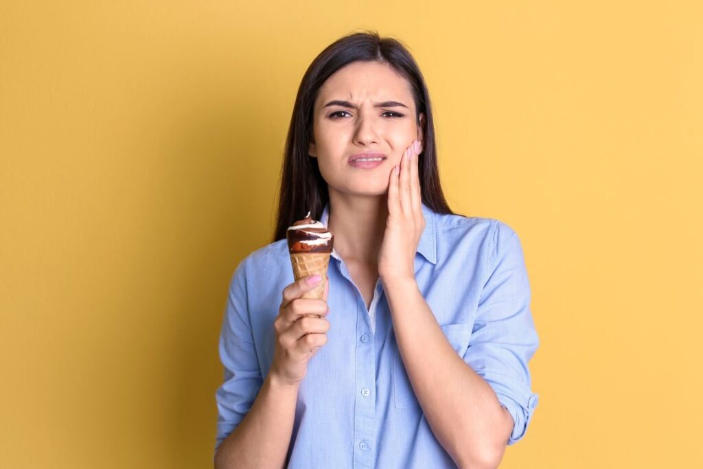 A woman with sensitive teeth eating an ice cream cone.